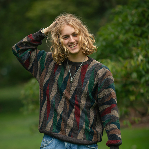 Calder smiling for the camera, posing outdoors in a sweater 