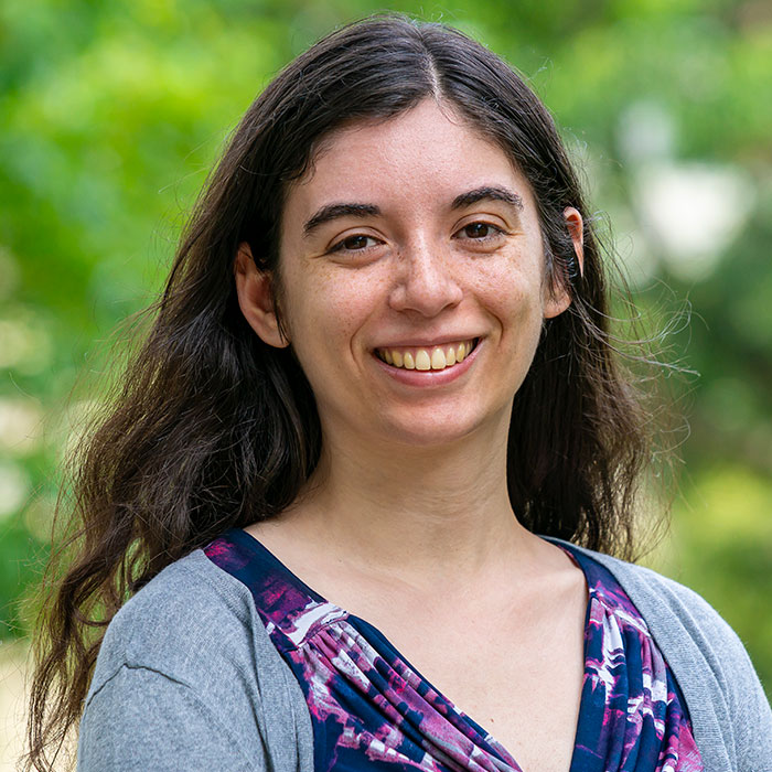 Headshot of Amy Miller smiling for the camera against a soft focus background of Haverford College foliage