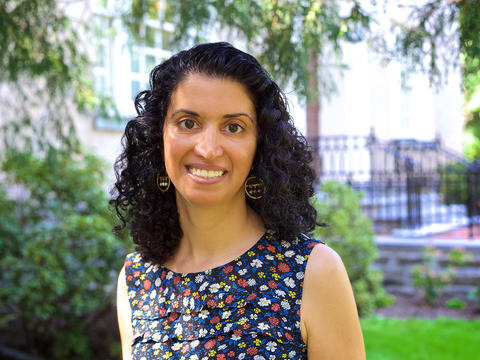 Zainab-Saleh in a floral print top smiling for the camera with a soft focus background of Haverford College