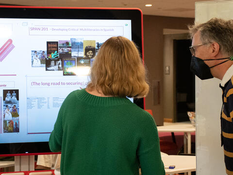 Librarian Mike Persick and a student presenter looking at a screen containing information regarding OER for the Libraries OER showcase.