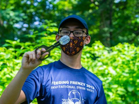 Theo Bi n wears a mask on the Nature Trail while handling a spotted lanternfly specimen