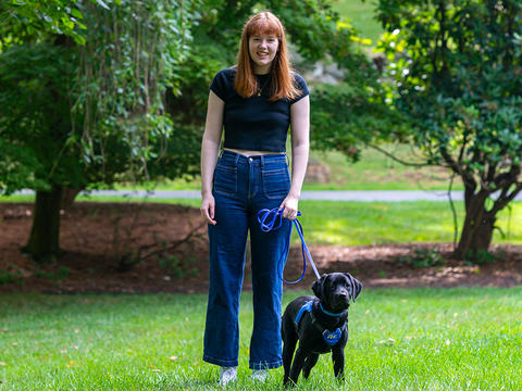 Aileen King is pictured in a portrait with a small black lab puppy. 