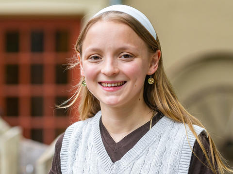 Isabella Otterbein is pictured in a portrait wearing a white headband and a white sweater over a dark-colored shirt. 