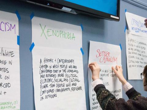 students place notes about social justice issues on a wall