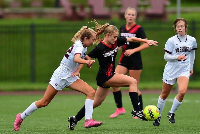 Olivia D'Aulerio, wearing a black and red Haverford soccer uniform, dribbles past a defender during a fall soccer match. 