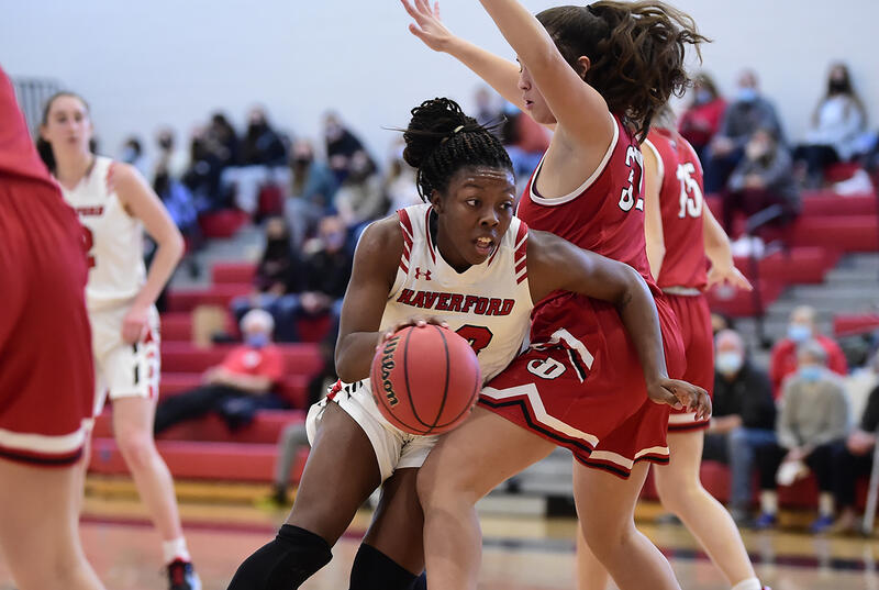 A women's basketball player drive to the hoop while wearing a white Haverford uniform.