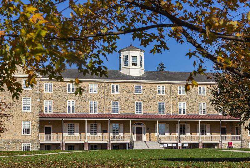 Wide shot of Founders Hall and Green framed by fall foliage