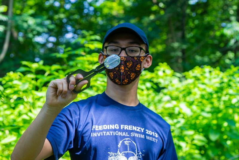 Theo Bi n wears a mask on the Nature Trail while handling a spotted lanternfly specimen