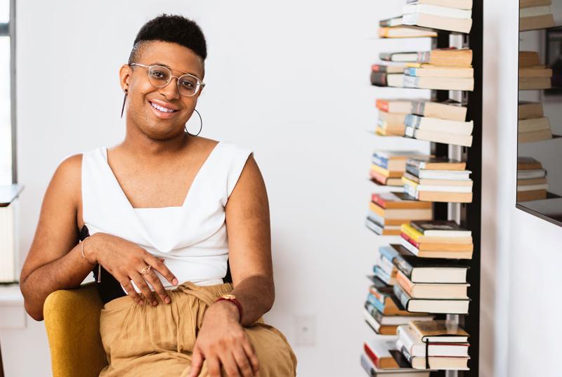 Denne Michele Norris sits in her home office next to bookshelves full of books. 