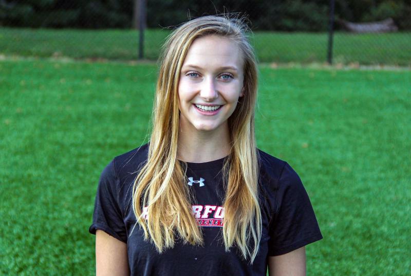 Headshot of Julie wearing a Haverford Field Hockey shirt on a green field.