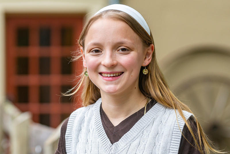 Isabella Otterbein is pictured in a portrait wearing a white headband and a white sweater over a dark-colored shirt. 