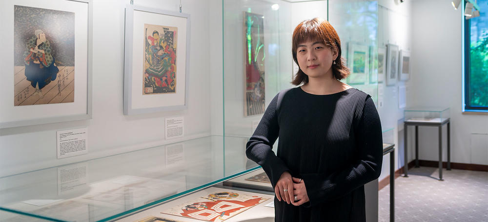 Stephanie Wang standing among prints at the Beyond the Floating World exhibit