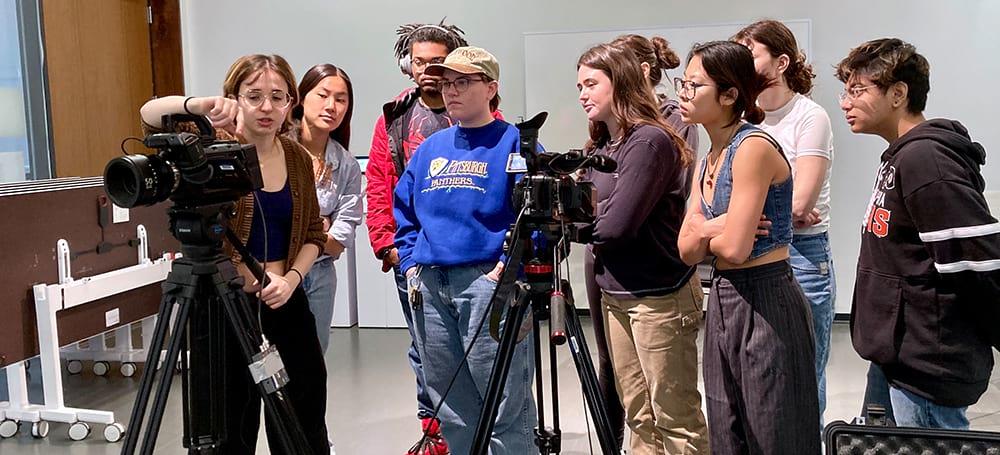 A teaching assistant demonstrating to students in John Muse’s Visual Studies course Film on Photography to use camera equipment.
