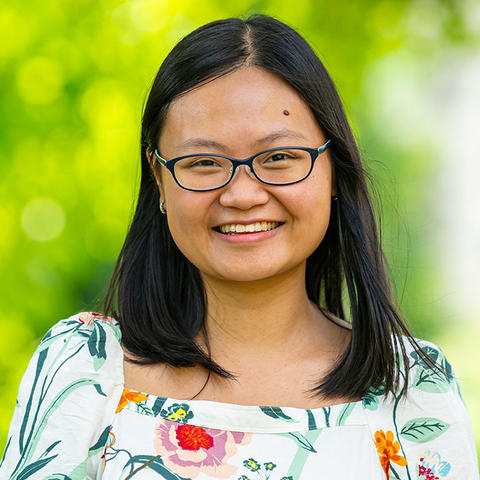 Thao Nguyen smiling for the camera in a floral print top and glasses against a soft-focus nature background