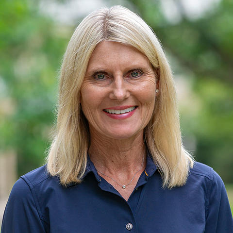 Headshot of Jill Miller smiling for the camera against a soft focus background of Haverford College foliage