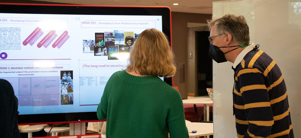 Librarian Mike Persick and a student presenter looking at a screen containing information regarding OER for the Libraries OER showcase.