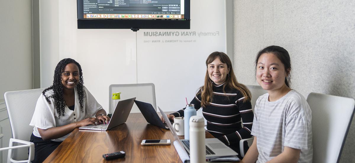 The three women who make up the Gradual incubator team work at laptops on their project