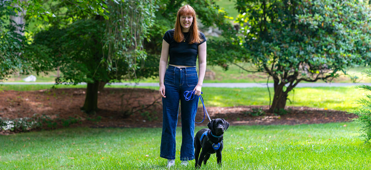 Aileen King is pictured in a portrait with a small black lab puppy. 