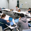 Students work on their finals while seated at tables forming a large rectangle.